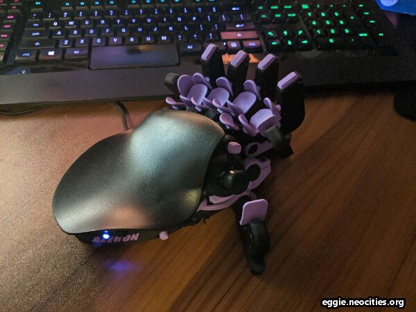 A picture of a left-handed Azeron Cyborg game pad with purple keys. It has a black, curved palm rest, 22 keys that are accessible from the four fingers, one two thumb buttons and one thumb joystick. It looks like some sort of alien technology.