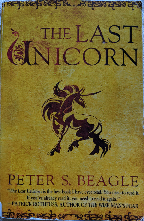 Book cover for The Last Unicorn by Peter S Beagle. The background resembles yellowed parchment, and in the center is a picture of The Unicorn from the book. At the bottom is a quote from Patrick Rothfuss, Author of The Wise Man's Fear. The Quote reads: The Last Unicorn is the best book I have ever read. You need to read it. If you've already read it, you need to read it again.
