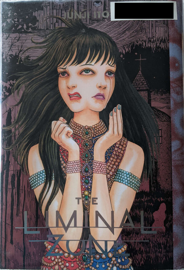 Cover for Ito Junji's The Liminal Zone. Artwok shows a woman with long black hair and green eyes, with two faces side by side, sharing the middle eye. Her expression on the left has her red lips curled in anger. The face on the right has a long line of tears flowing from the non-shared eye, her purple lips forming a frown. She is wearing an elaborate sleeveless dress adorned with beads, gold filigree, and precious gems. On her upper arms are five, blue beaded bracelets on each arm, and on each wrist are six bracelets with pink beads. Her left hand is opened with her fingers pointed up and her palm towards her face, and with her nails painted blue. Her right hand is clenched closed, with her nails painted red. The background is a collage of various secenes from the manga in a faded dark red.