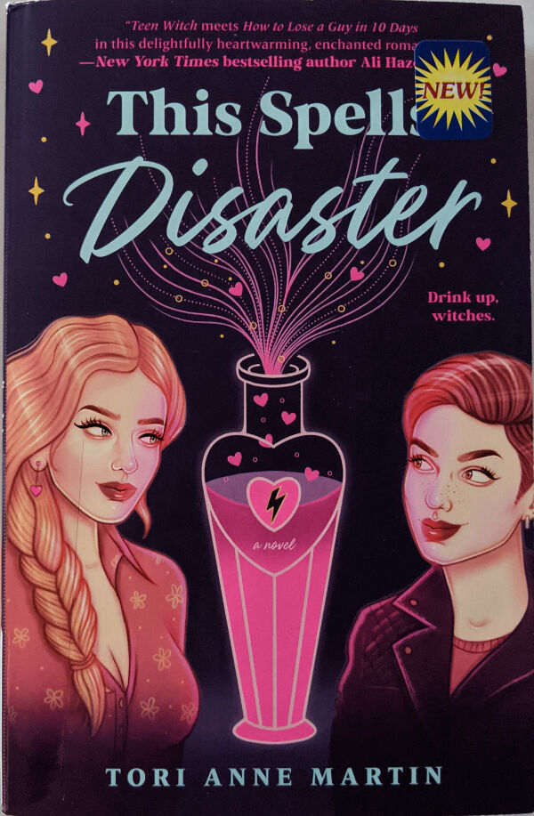 Book cover for This Spells Disaster. The title text is in light blue on a midnight purple background. At the bottom are the two main characters who are looking at each other. On the left is Morgan, who has long strawberry blonde hair pleated into a side braid over her shoulder, green eyes, pink heart earrings, and a pink floral blouse showing her cleavage. On the right is Rory, who has short brown hair with an undercut, brown eyes, an a black leather jacket with a red shirt underneath. Between them is an ornate potion bottle with a heart design containing a pink liquid that has hearts coming out of it. The text below the title reads: Drink up, witches.