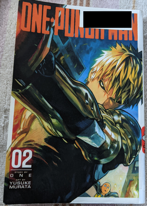 Cover for Volume Two of One Punch Man, written by One, Art by Murata Yusuke. Artwork a close up of Genos, his arm extended as if to fire his laser canon. Saitama is in the background, small as if far away, with an open mouthed smile on his face.