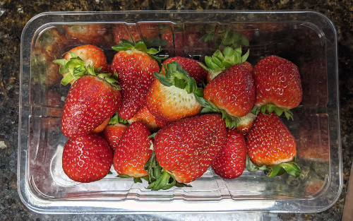A clamshell container of smuccies strawberries