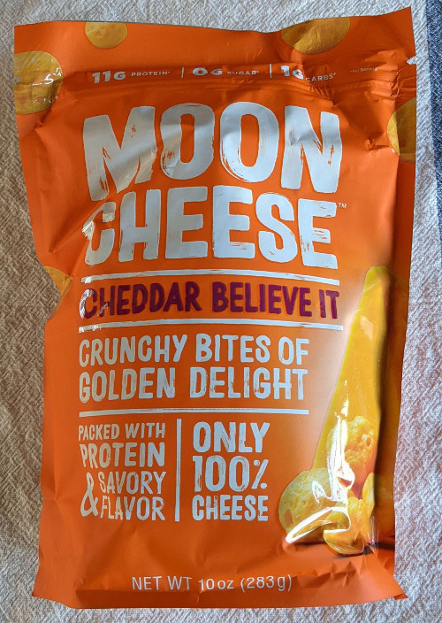 A packet of Moon Cheese Cheddar believe it flavor in 10 ounce size. The text on the package reads (from top to bottom) 11 grams protien. 0 grams sugar. 1 grams carbs. Moon Cheese Cheddar Believe it. Crunchy bites of golden delight. Packed with protien and savory flavor. Only 100% cheese.