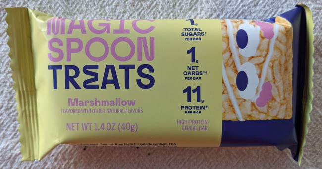 A single bar treat bar, still in package. Has the same text as the outer box. On the right side of the package there is the same cereal bar with eyes.